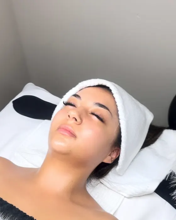 Client relaxing on the facial bed with her hair wrapped in a towel