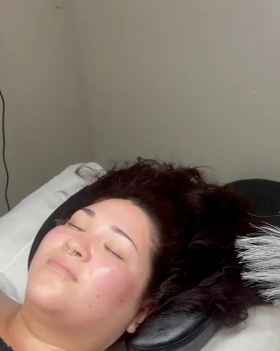 Client glowing after a facial, resting on the treatment bed