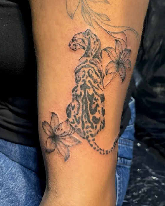 Black and grey leopard with lilies on the forearm
