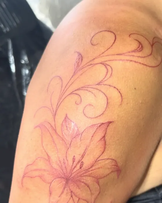 Red fine line lilies and swirls on the upper arm