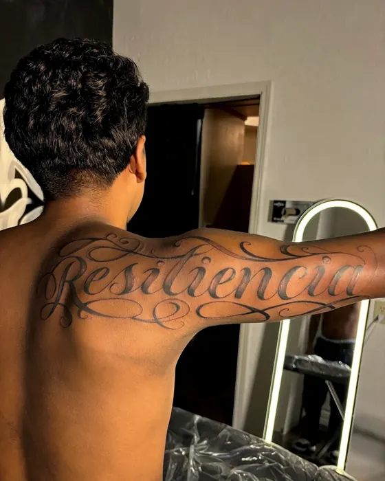 Large script lettering reading Resilencia across the shoulders