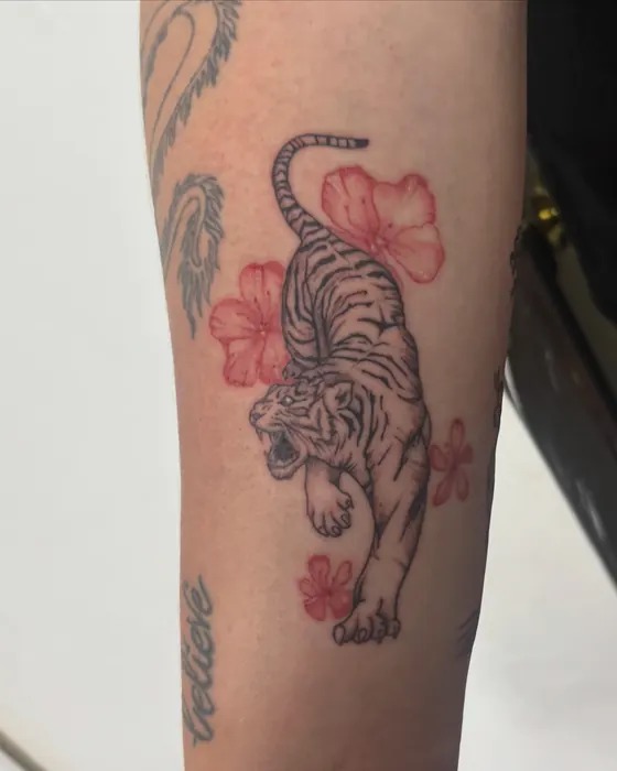 Tiger with red hibiscus flowers on the upper arm