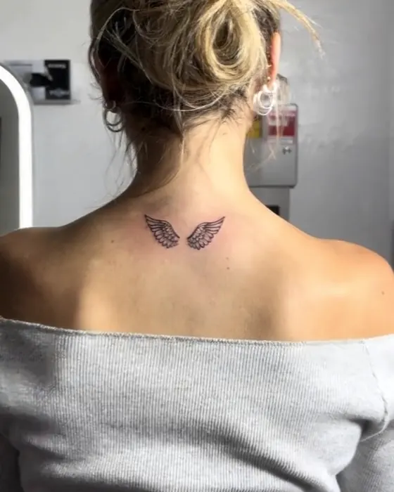 Tiny fine line wings at the base of the neck
