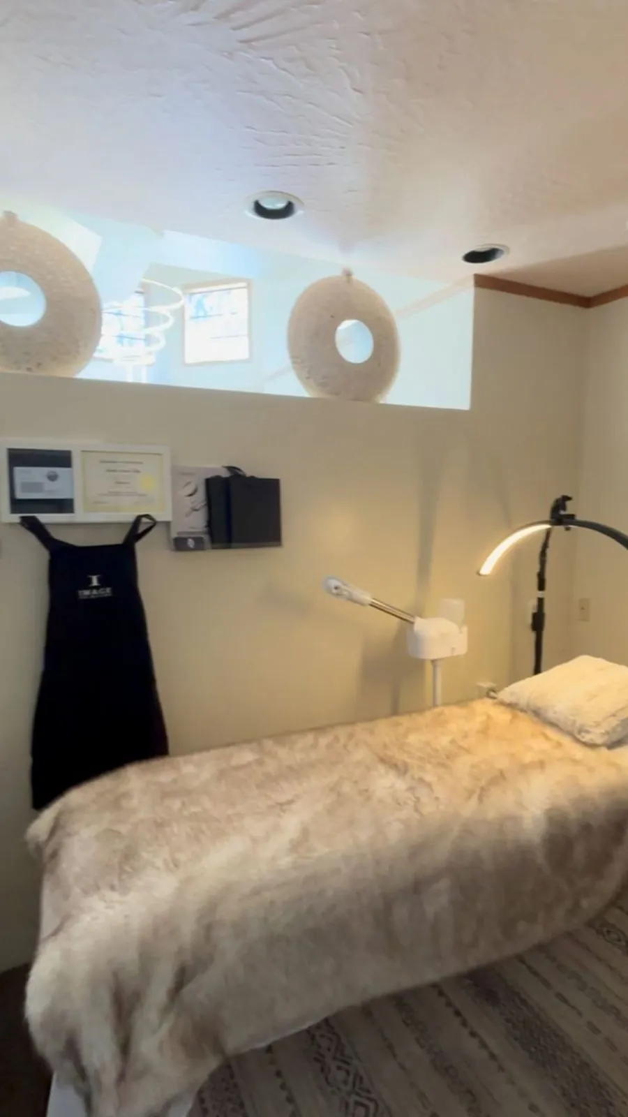 The BB Beauty treatment room: a facial bed with a soft cream throw, round mirrors and warm lighting