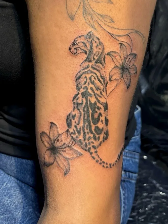 Black and grey leopard with lilies on the forearm