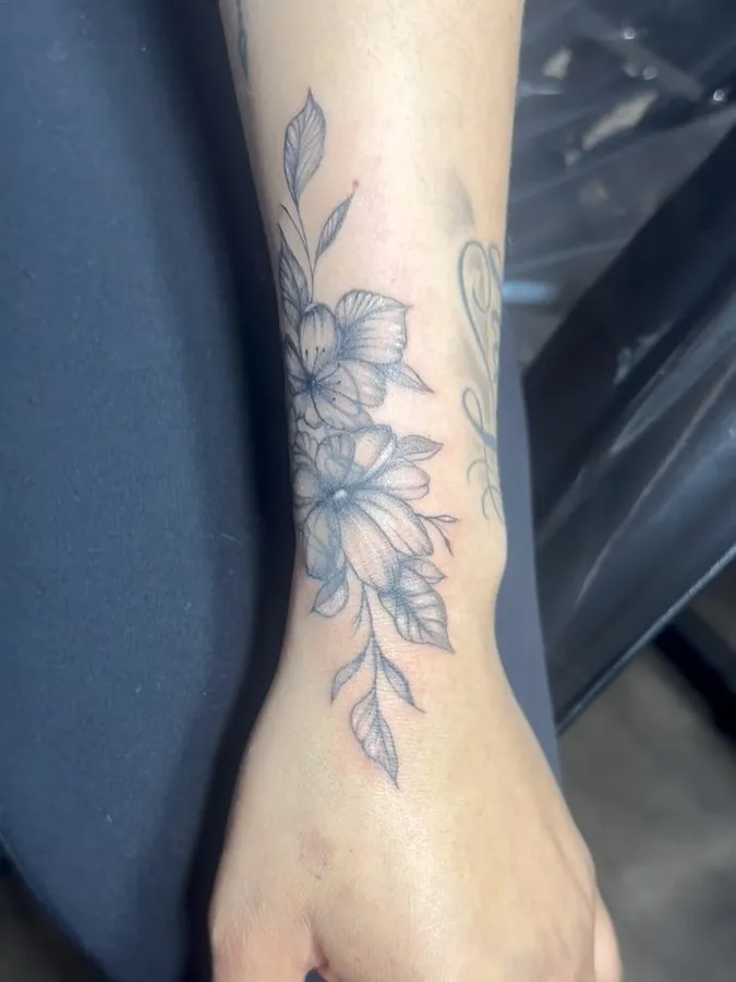 Fine line floral tattoo running from the wrist up the forearm