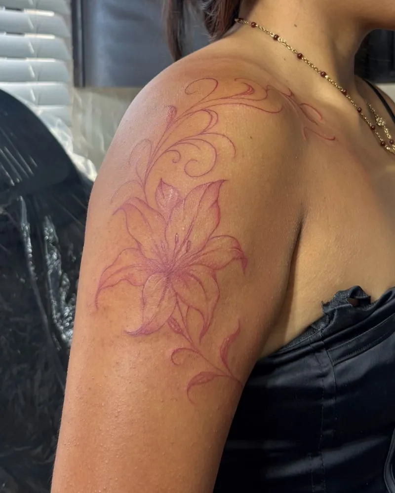 Red fine line lily and flourish tattoo on the shoulder
