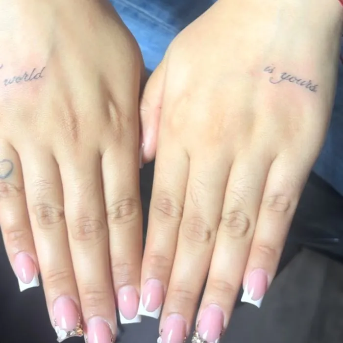 Tiny fine line script tattoos on the sides of two hands. View on Instagram.